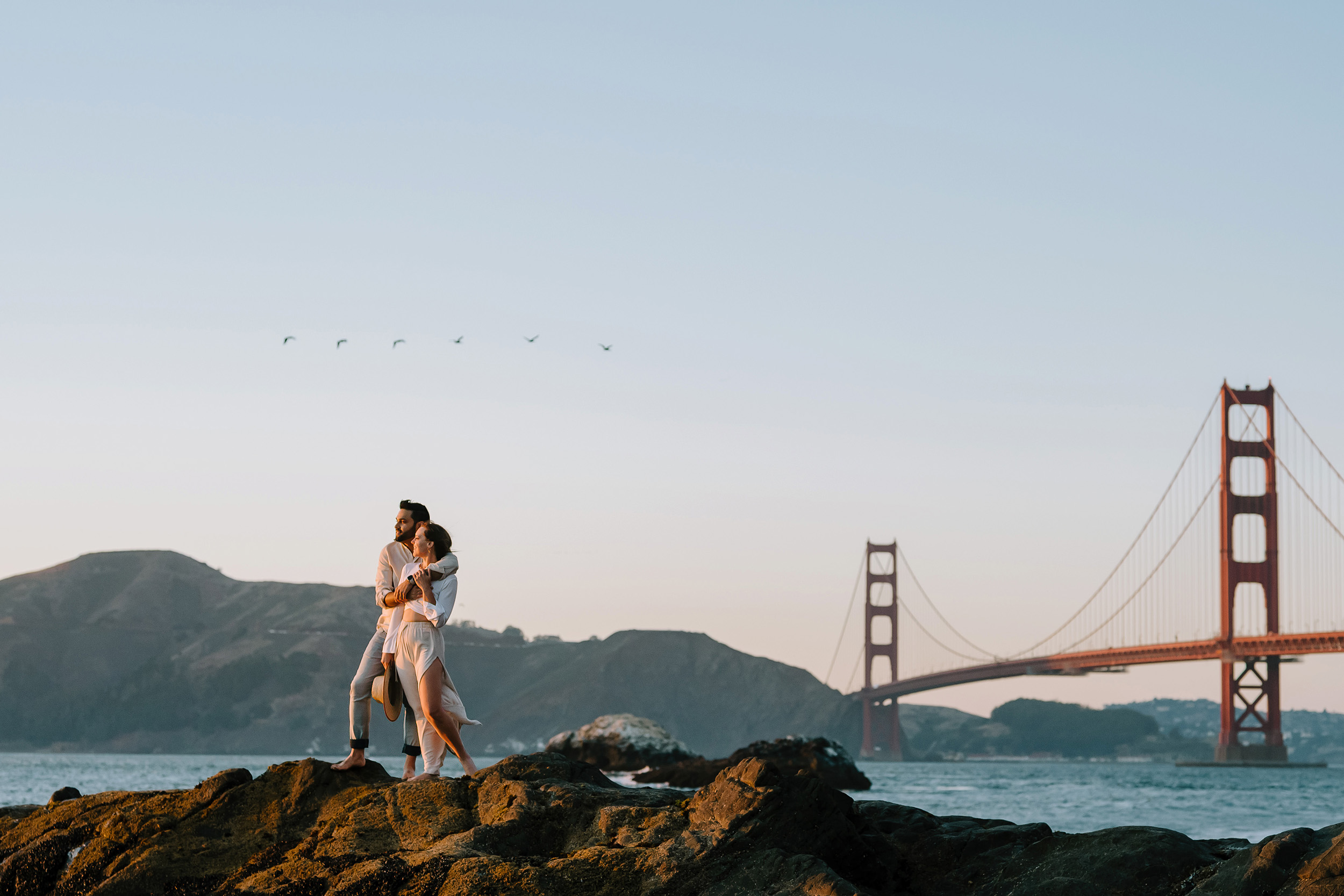 couple on the rocks with the Golden Gate Bridge in the background